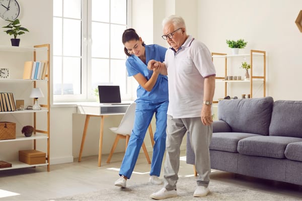 Nurse assisting an elderly man in a cozy living space