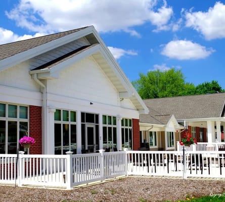 Exterior view of a senior living facility with flowers and benches