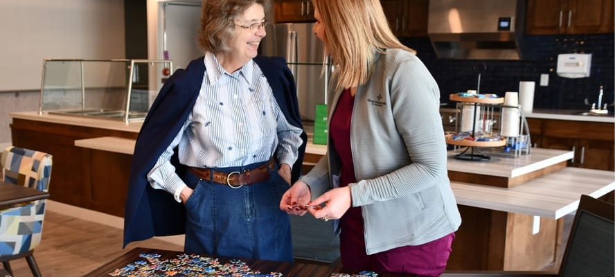 Residents and staff engaging over a puzzle in a common area