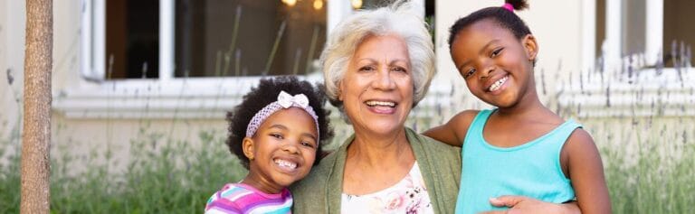 A happy senior woman with two smiling children outdoors