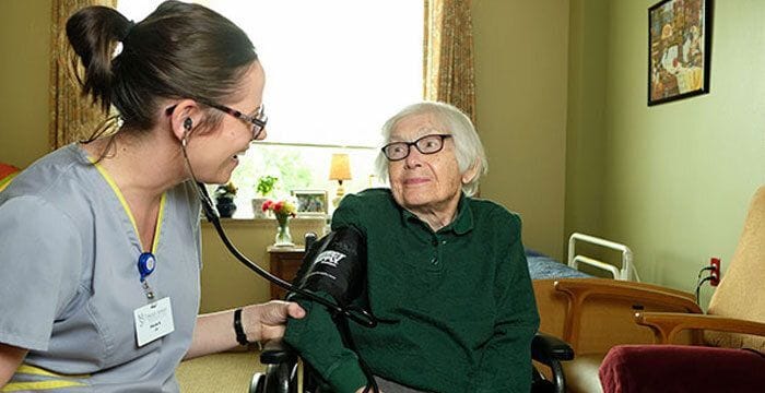 Nurse checking blood pressure of a resident in a room