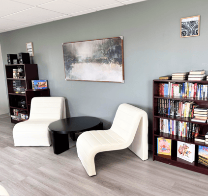 A cozy reading area with white chairs and bookshelves