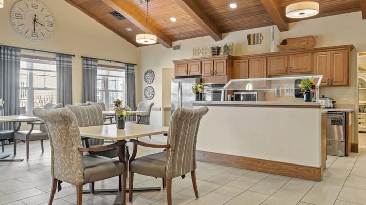 Dining area with tables and kitchen in assisted living facility