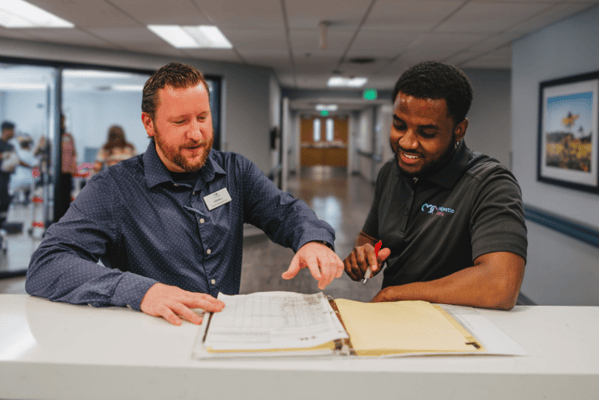 Staff members engaging in conversation over paperwork