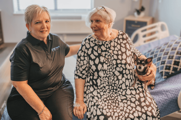 Staff member smiling with a resident and her dog