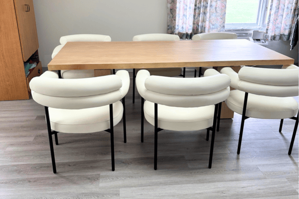 A bright dining area with white chairs around a wooden table