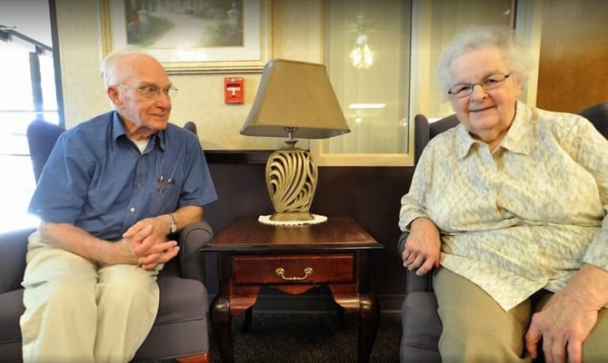 Two residents sitting together in a cozy lounge