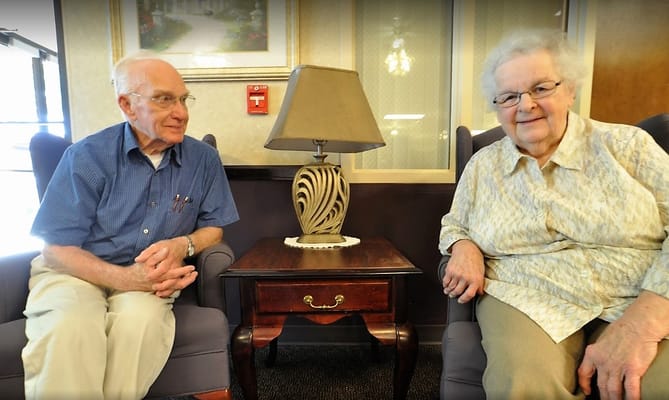 Two residents sitting together in a cozy lounge