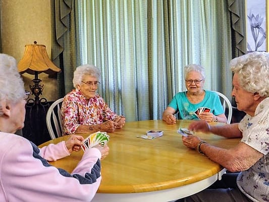 Residents playing cards at a table in a cozy room