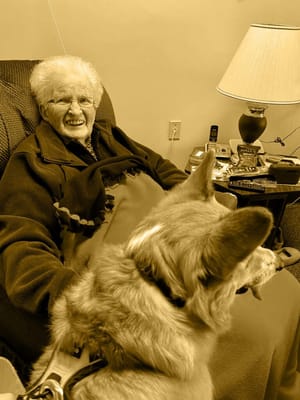 Resident smiling with a dog in a cozy room
