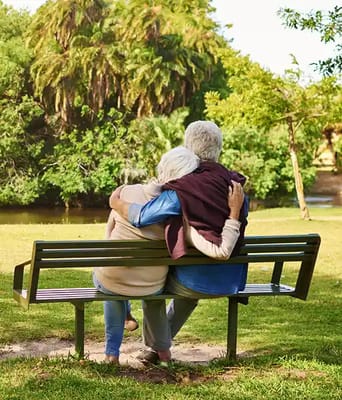 Elderly couple sitting on a bench in a garden