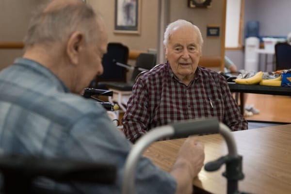 Two seniors conversing at a dining table