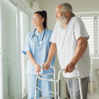 Nurse assisting a resident with a walker indoors