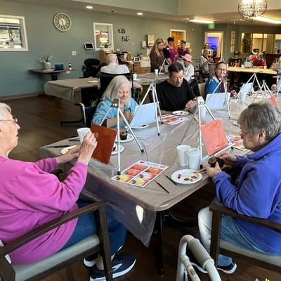 Residents participating in a painting activity at a communal table