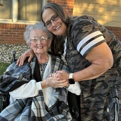 Senior resident smiling with staff member outdoors