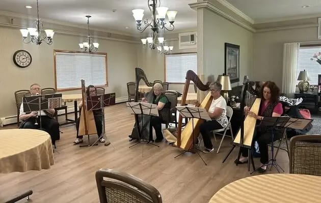 Residents playing harps in a cozy common area