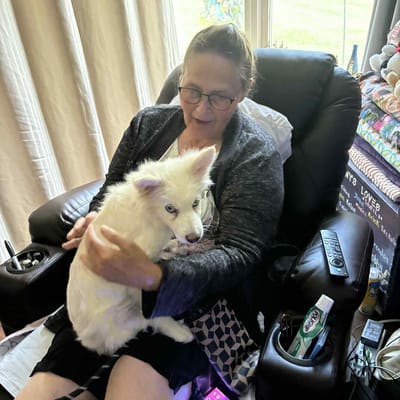 Resident holding a fluffy white dog in a cozy chair