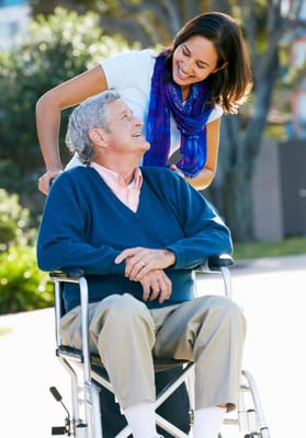 A caregiver interacting with a resident in a wheelchair outside