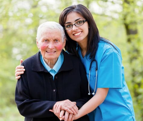 A caregiver and a senior resident smiling outdoors