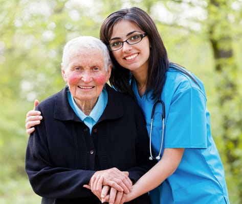 A caregiver and a senior resident smiling outdoors