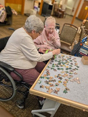 Two residents assembling a puzzle in a common area