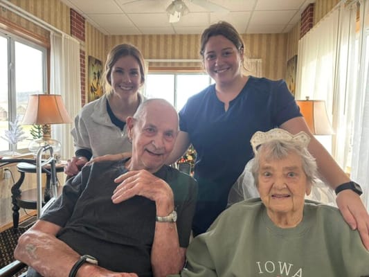 Two residents with staff in a bright common area