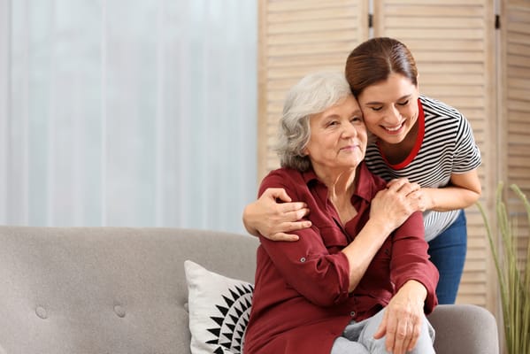 A caregiver hugging a resident on a sofa
