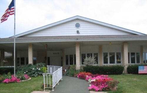 Front entrance of a senior living facility with flowers and flags