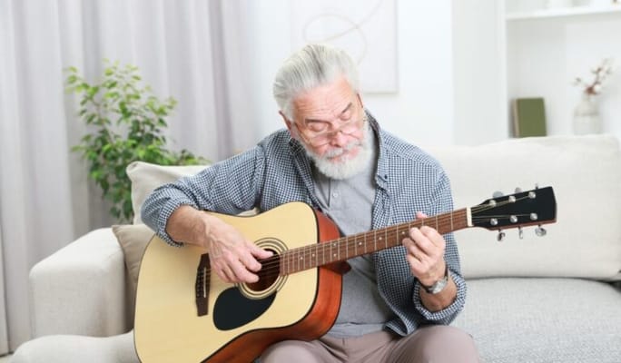 Senior man playing guitar in a cozy lounge