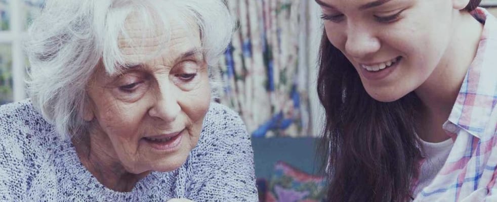 Senior resident engaged with staff member in a warm setting