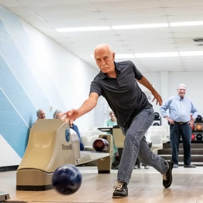 A resident bowling with others watching in the background