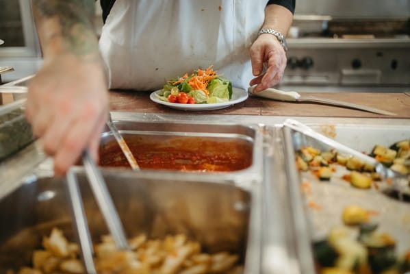 A hand serving a fresh salad in a kitchen
