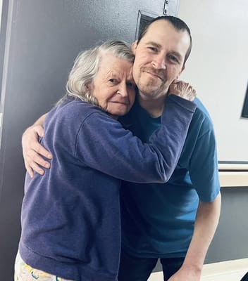 A resident and a staff member sharing a warm embrace