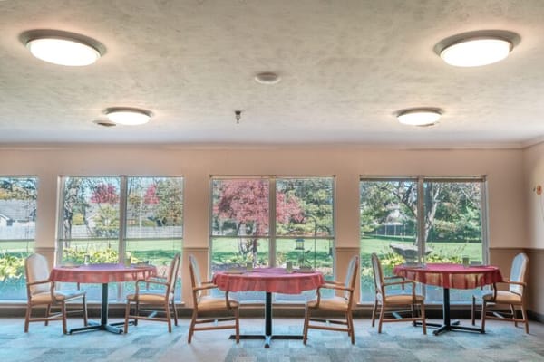 Dining area with tables and large windows overlooking the garden