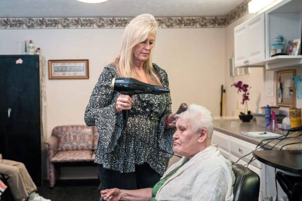 Stylist drying resident's hair in a treatment room