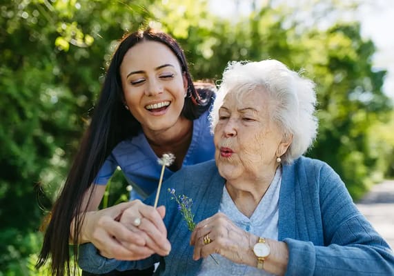 A caregiver assisting a resident outdoors with flowers