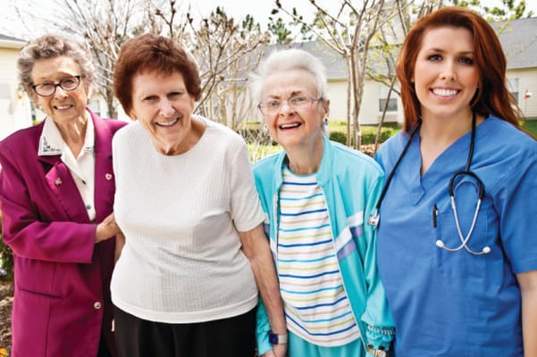 Four smiling women, including staff and residents, outdoors
