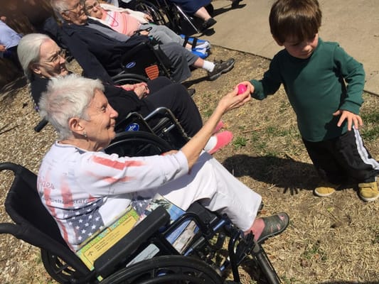 A senior woman in a wheelchair interacting with a child outdoors