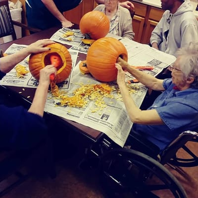 Residents carving pumpkins at a table during an activity