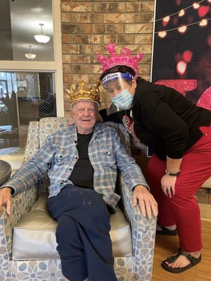 Resident and staff member celebrating with crowns in a common area