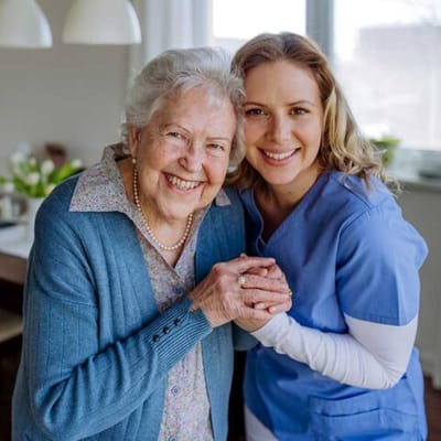 A happy resident and caregiver smiling together
