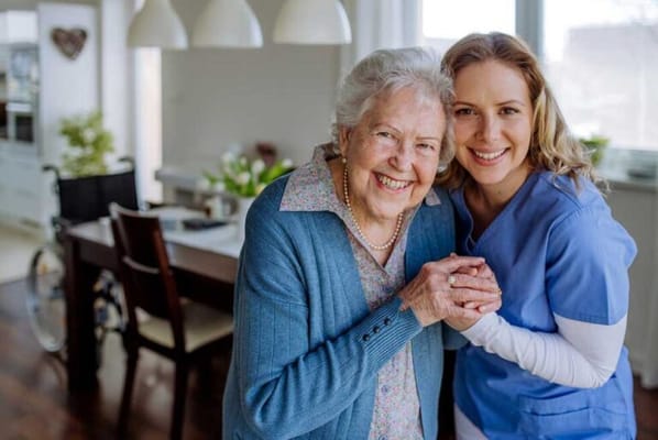 A caregiver and resident smiling together in a cozy living area