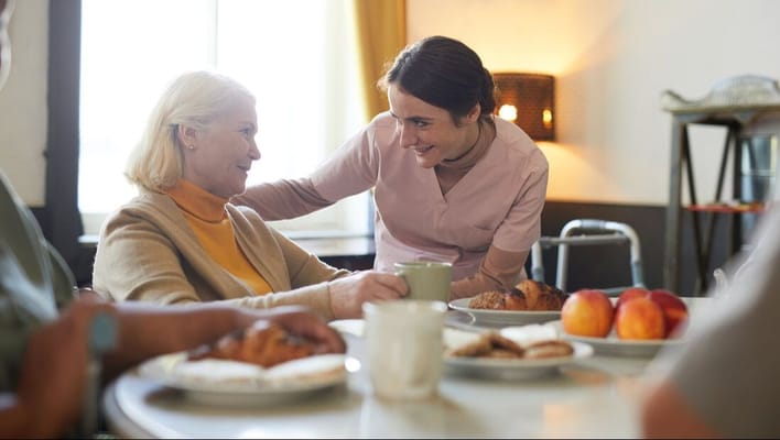 Staff serving food to a resident in the dining area