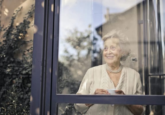 Senior woman smiling while looking out a window