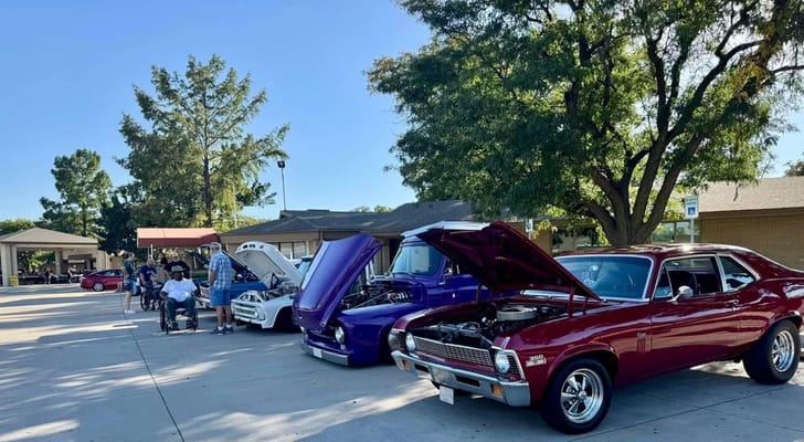 Car show featuring classic vehicles with residents watching