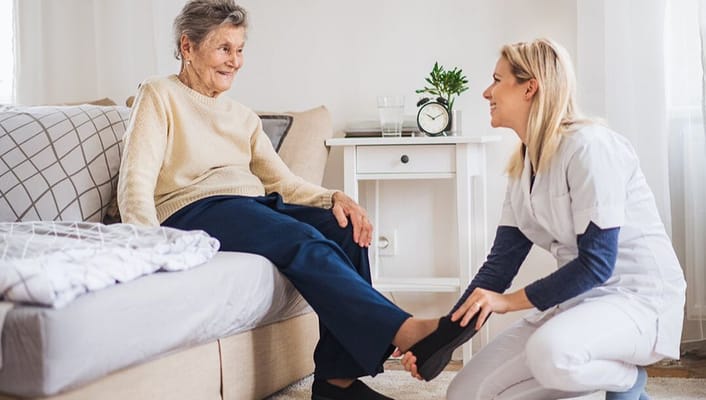 A caregiver assisting an elderly resident in a cozy room