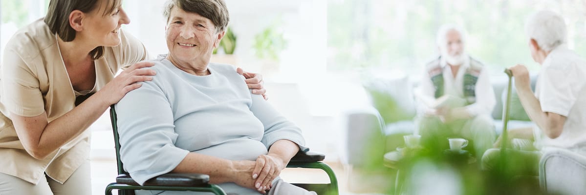 Caregiver assisting a smiling resident in a common area