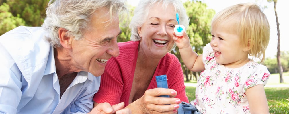 Seniors enjoying a playful moment with a child outdoors