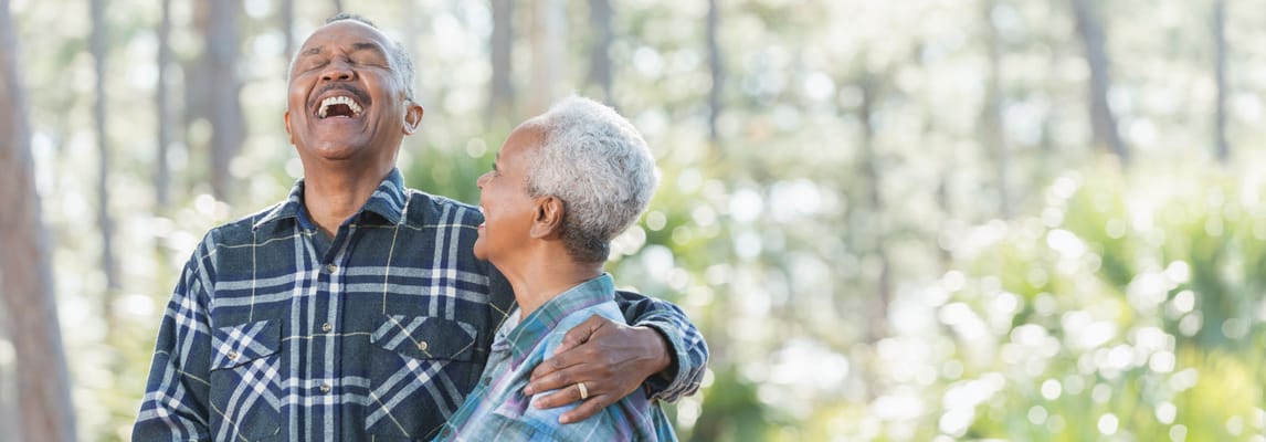 Two seniors laughing joyfully in a natural setting