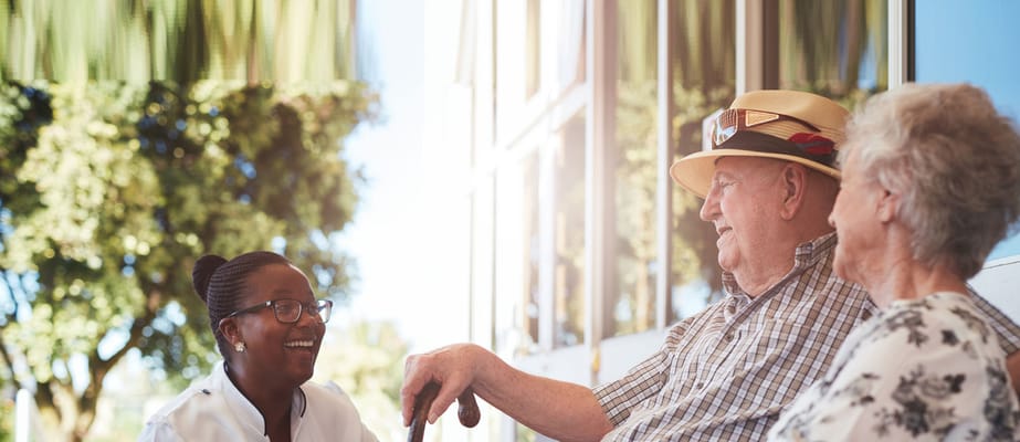 Resident interacting with staff outdoors in a sunny space